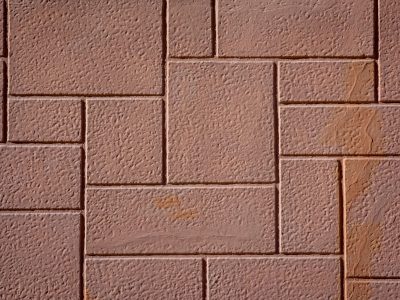 Close-up view of textured brown concrete paving stones arranged in an interlocking pattern.
